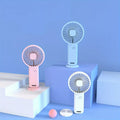 Three portable hand fans in pink, blue, and white on a blue background
